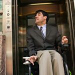 Mężczyzna na elektrycznym wózku inwalidzkim opuszczający windę