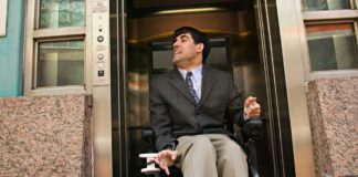 Mężczyzna na elektrycznym wózku inwalidzkim opuszczający windę