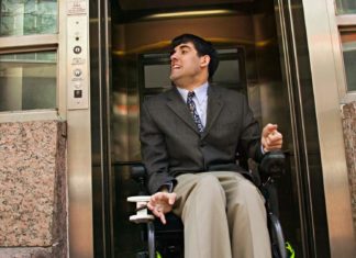 Mężczyzna na elektrycznym wózku inwalidzkim opuszczający windę