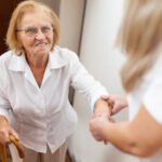 Asystentka pomagająca starszej kobiecie wejść po schodach