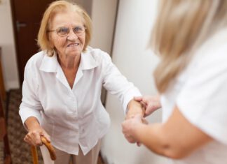 Asystentka pomagająca starszej kobiecie wejść po schodach