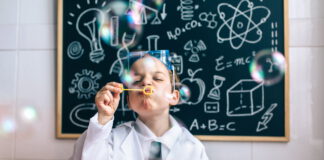 Chłopczyk dmuchający bańki mydlane przed tablicą szkolną