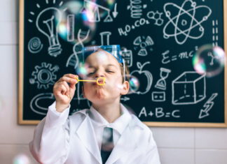 Chłopczyk dmuchający bańki mydlane przed tablicą szkolną