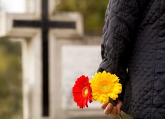 Cmentarz i koronawirus Mężczyzna z kwiatami na cmentarzu