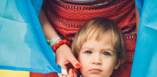 dziecko, za nim mama , flaga żółto-niebieska