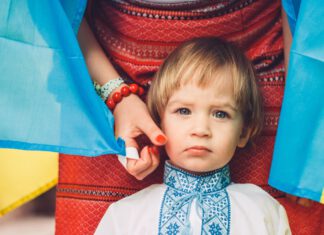 dziecko, za nim mama , flaga żółto-niebieska