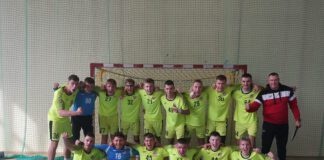 zadowolona drużyna piłki ręcznej pozuje do zdjęcia przed bramką