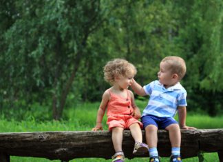 Światowy Dzień Życzliwości i Pozdrowień dwoje małych dzieci siedzi na przewróconym drzewie