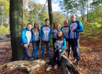 zawodnicy z medalami pozują do zdjęcia w lesie