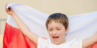 dziecko trzyma z tyłu flagę Polski