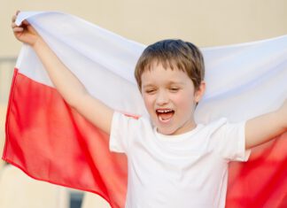 dziecko trzyma z tyłu flagę Polski