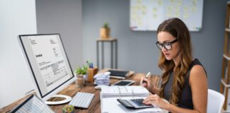 Księgowa przy biurku przed ekranem liczy na kalkulatorze