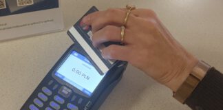 terminal płatniczy oraz zbliżona do niego ręka z kartą płatniczą