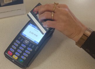 terminal płatniczy oraz zbliżona do niego ręka z kartą płatniczą