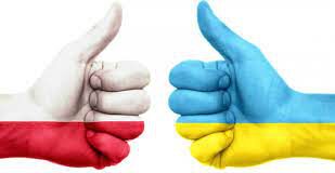 dwie dłonie pomalowane w kolorach flagi polskiej i ukraińskiej